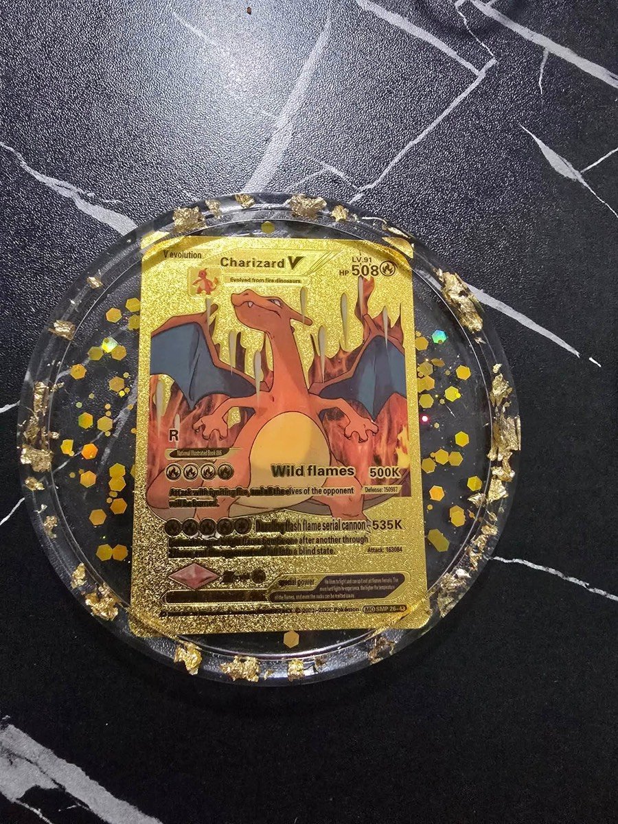 Round resin coaster with a Charizard V trading card and gold flake trim