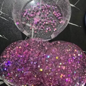 Three round resin coasters in shades of pink glitter