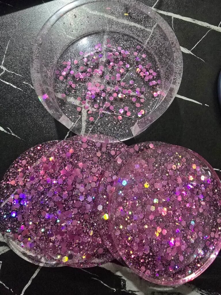Three round resin coasters in shades of pink glitter