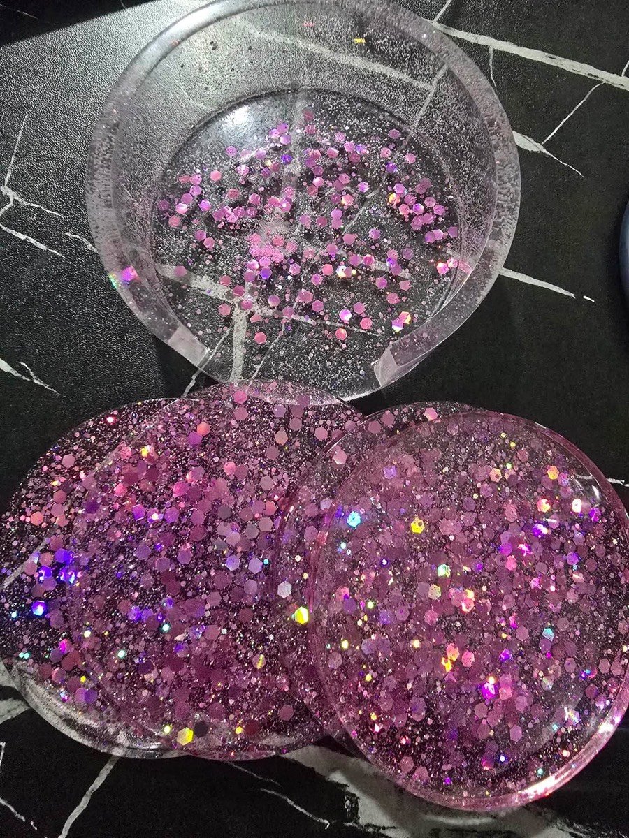Three round resin coasters in shades of pink glitter