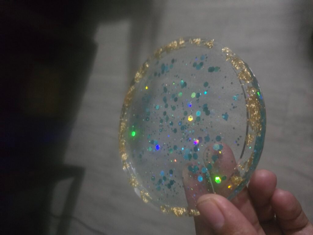 Clear resin coaster with holographic glitter confetti and a gold leaf edge