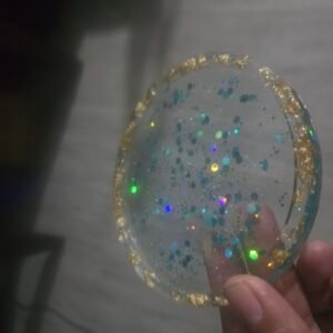 Clear resin coaster with holographic glitter confetti and a gold leaf edge